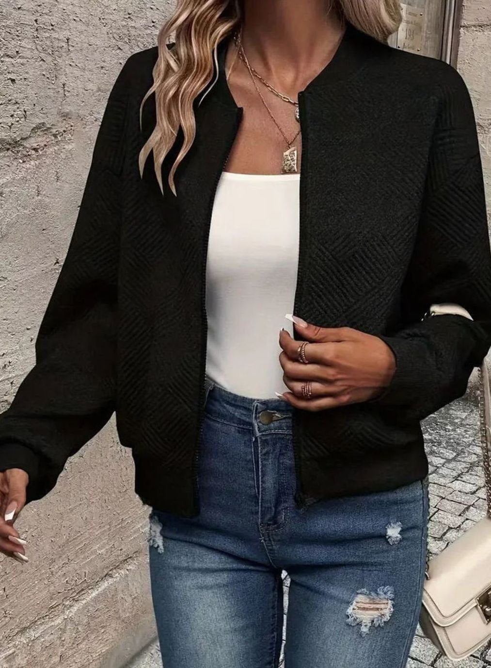 Mujer luciendo el cárdigan bomber combinado con vaqueros y zapatillas