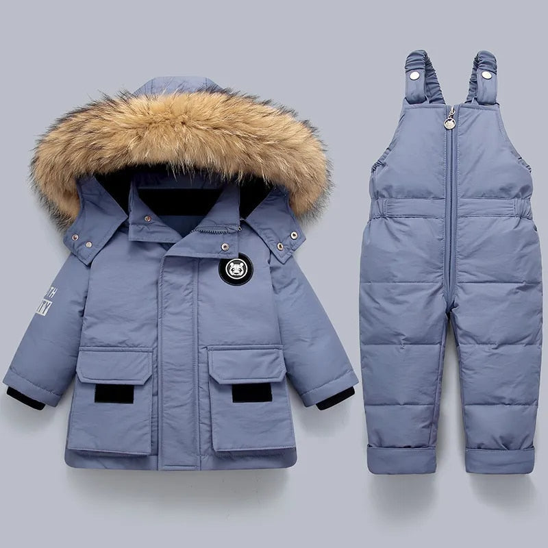 Niña jugando en la nieve con el conjunto de invierno FROSTVYN