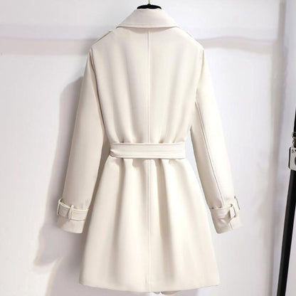 Detalle de botonadura cruzada dorada y cinturón ajustable en gabardina blanca