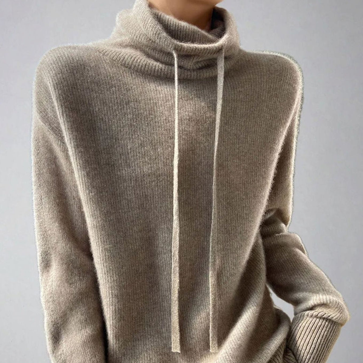 Mujer con jersey holgado de cuello alto y cordón ajustable en tono khaki