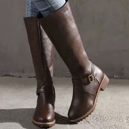 Botas altas de piel negra hasta la rodilla combinadas con vaqueros